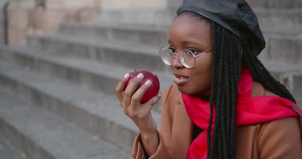 Young Black Girl Eating an Apple on the Stairs