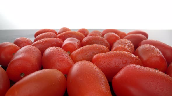 Ripe Red Biological Tomatoes in a Row on a Smooth Glass Surface