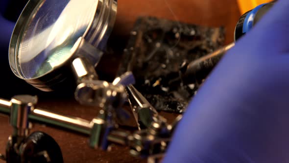 Person in Sterile Gloves Solders Looking Through Magnifier