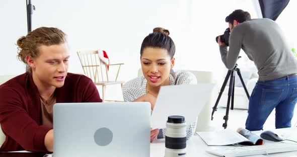 Photographer and female model discussing over laptop