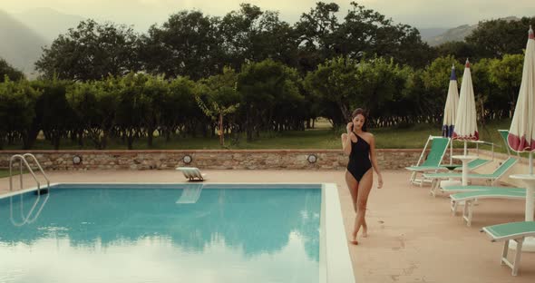 Girl with black swimsuit walk beside the pool