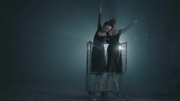 The Figures of Two Slim Professional Ballerinas Dancing in Black Dress in the Studio Inside Big Blue