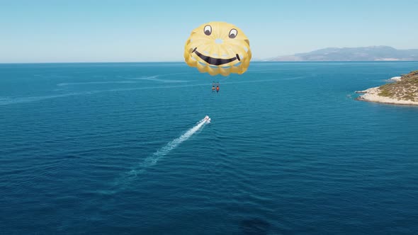 Drone flight next to parachutists engaged in parasailing. The parachute is tied to a motor boat.