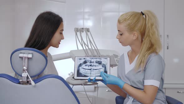 Dentist and Patient Choosing Treatment in a Consultation with Medical Equipment in the Background