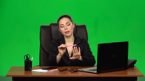 Girl at Workplace Is Working on Laptop, Talking on Phone and Sawing Nails. Green Screen. Slow Motion