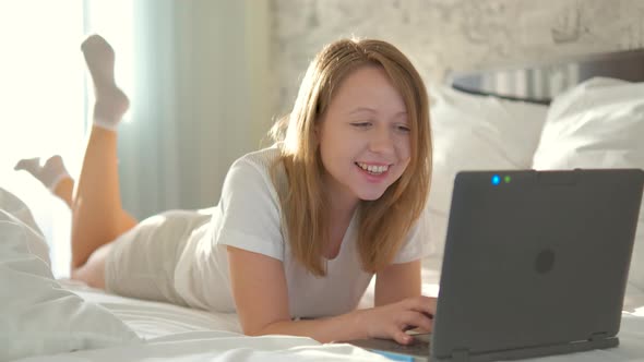 Portrait of a girl in casual clothes looks at the laptop screen.