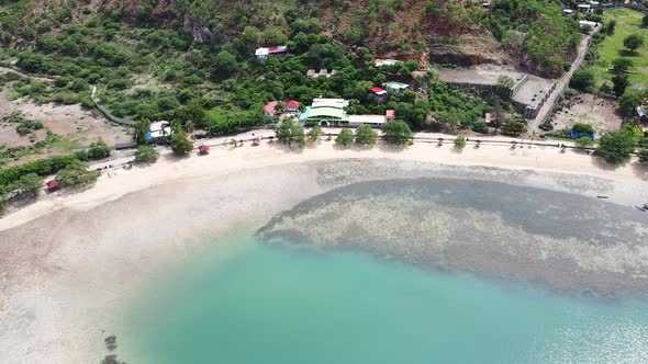 Aerial static drone of motorbike cruising along the coastal road on tropical island Timor Leste, Sou