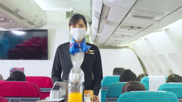 Cabin crew wear mask, pushing service cart and serve to customer on the airplane during flight.