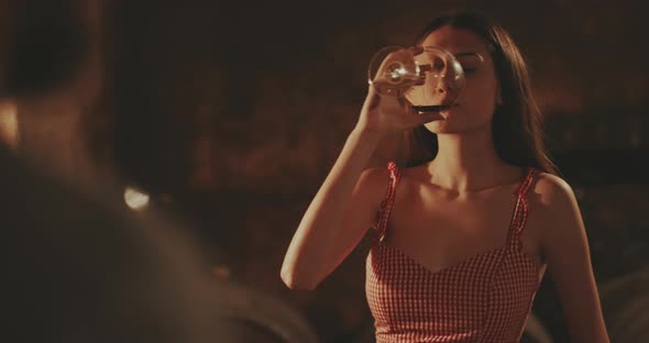 Young woman taking a sip of red wine and smiling