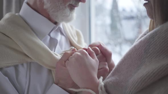 Close-up of Senior Man Kissing Female Caucasian Hands and Smiling. Unity of Loving Couple with Age
