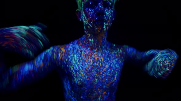 Man Covered with Phosphor Paint Dances Under Ultraviolet Light in Studio on Dark Background Front