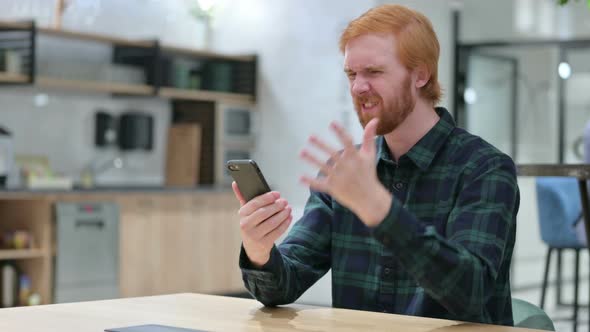 Unhappy Beard Redhead Man with Loss on Smartphone in Cafe 