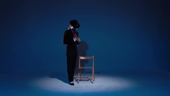 Elegant Man in a Black Hat Is Dancing an Erotic Dance. Spotlight on a Blue Background. Close Up