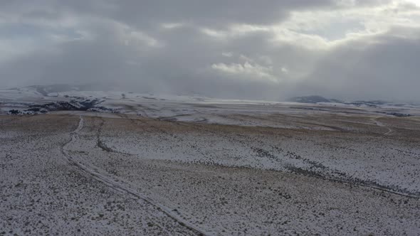 Panning tracking drone shot of expansive plains and snowy landscape