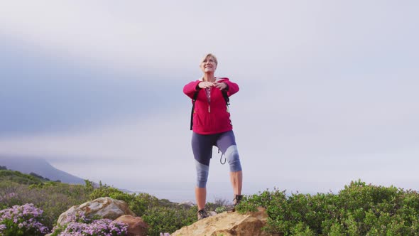 Senior hiker woman standing with her arms wide open standing on a rock