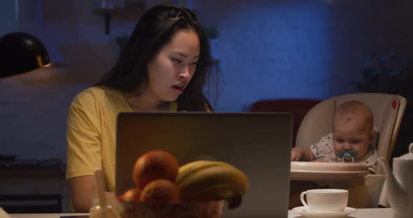 Young Mother with Baby Working on Laptop