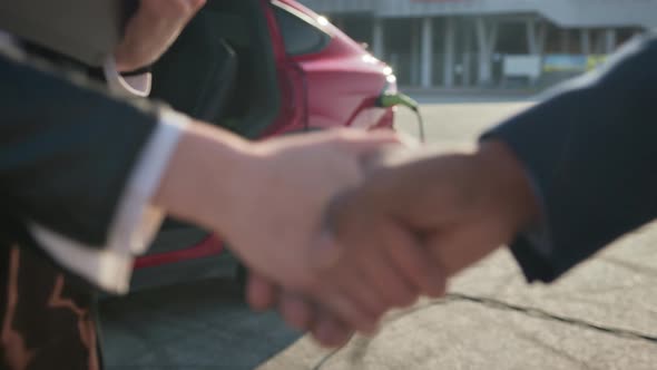 Man Shaking Hands with Woman While Buying Electric Car