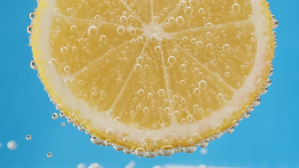 Lemon Slice in Carbonated Water on Blue Background Fizzy Summer Drink Making Cocktail of Citrus