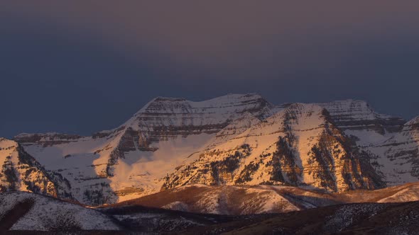 Sunlight moving on snow covered mountains during sunrise in Utah