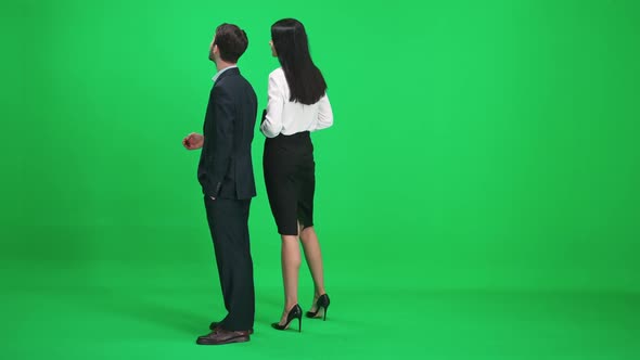 Man and Woman in Suits Stands in the Green Space of the Chromakey They Discuss Subjects While