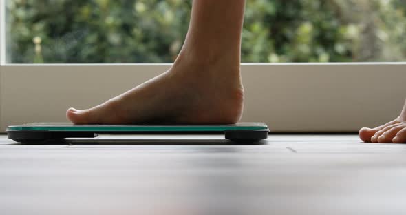 small, thin woman's feet get on and off a bathroom scale