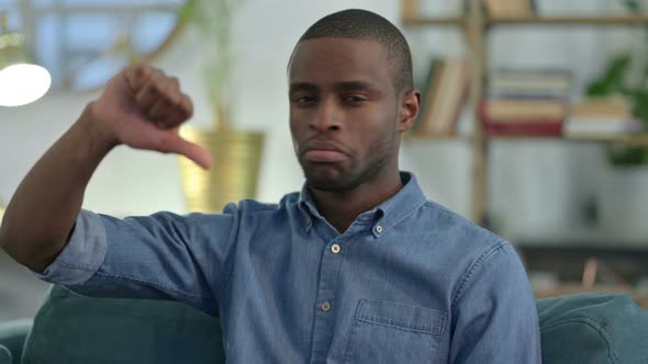 Young African Man with Thumbs Down at Home 