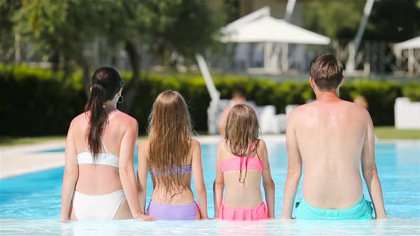 Happy Family of Four in Outdoors Swimming Pool