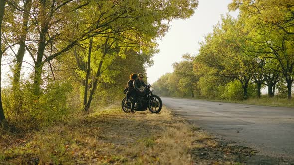 Young Attractive Couple Starting to Ride a Motorcycle Traveling Together on the Asphalt Road on a