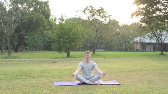 Young Happy Man Meditating with Eyes Closed at the Park