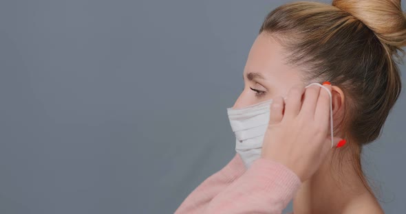 Young Woman Puts White Disposable Mask on Face and Fixes