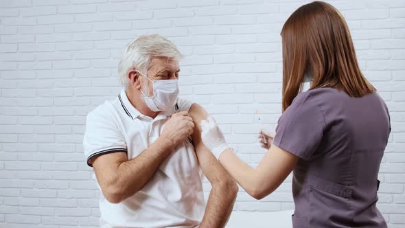 Female Nurse Giving Injection To Senior Man