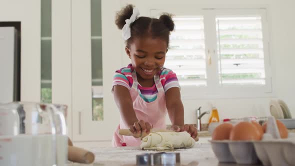 Happy african american girl rolling dough in kitchen