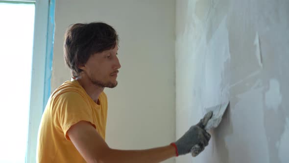 A Young Man in a Yellow Tshirt is Doing a Walls Renovation in His Home