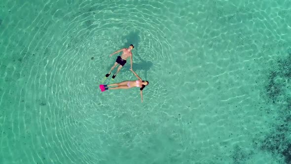 Aerial view of man and woman with masks and flippers swimming on their backs.