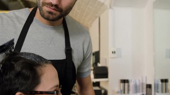 Hairdresser dyeing hair of client