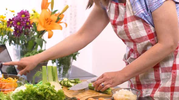 Woman In Kitchen Following Recipe On Digital Tablet