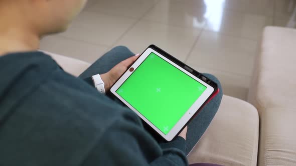 Girl looks at the green screen of the tablet