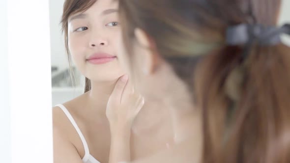 Beautiful young asian woman looking mirror and apply lotion sunscreen with neck.