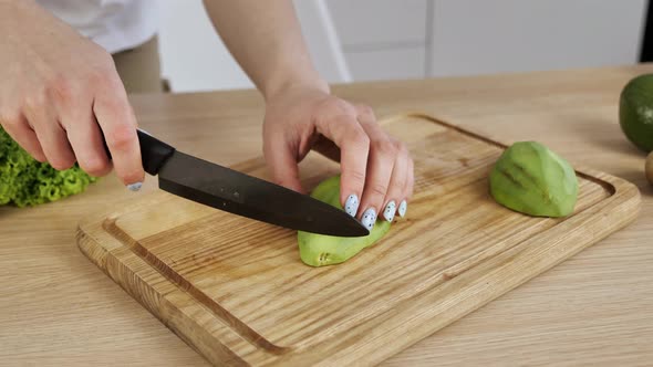 Female Hands Cut Avocado in Pieces