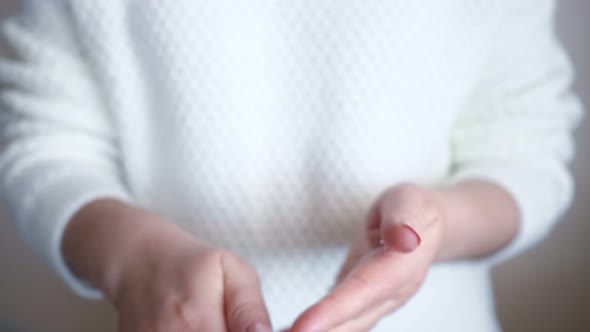 Unrecognizable Woman in White Sweater Smears Hands with Cream