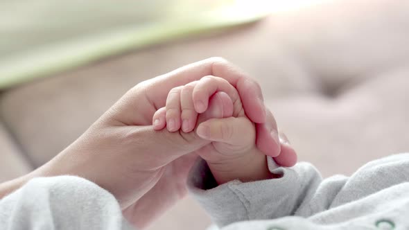 Newborn Baby Hand Holding Mother Mom Touching Baby Tiny Hand to Make Him Feeling Her Love Warm and