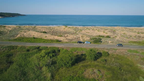 Drone Follows a Car on Beautiful Sea Road with Dunes and Calm Sea