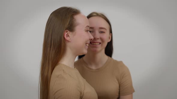 Laughing Young Woman Posing with Twin Sister at Background Side View