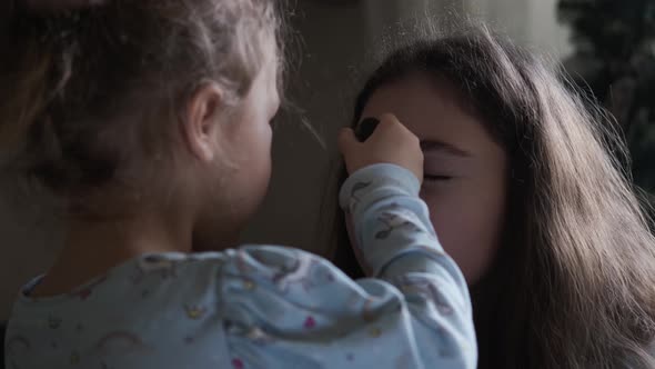 Little Girl Plays with a Makeup Brush and Imagines How She Is Doing Makeup To Her Friend