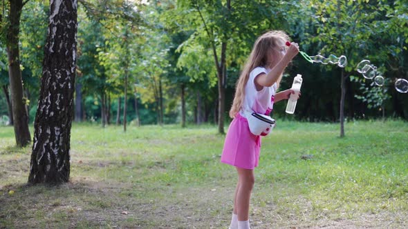 Side view of girl with bubble blower outdoors.