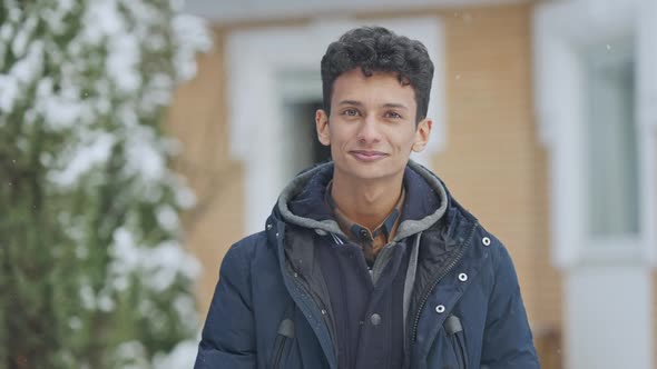 Relaxed Happy Middle Eastern Teenager Standing Outdoors on Snowy Day Looking at Camera and Smiling