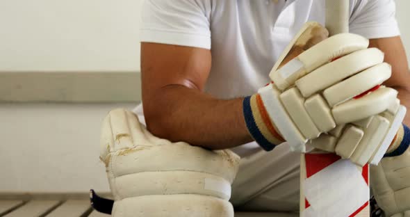 Cricket player sitting on bench in dressing room