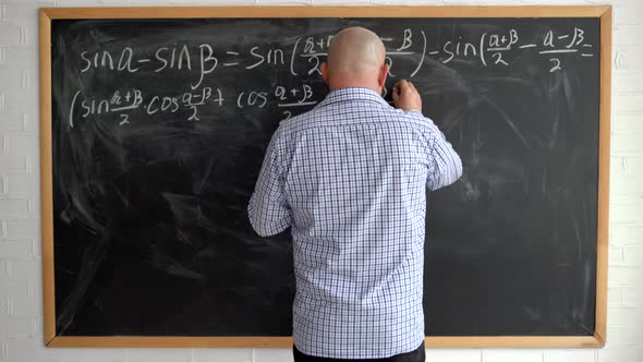 The Teacher at the Blackboard is a Man of 40s Without a Face Writing Down Mathematical Formulas with