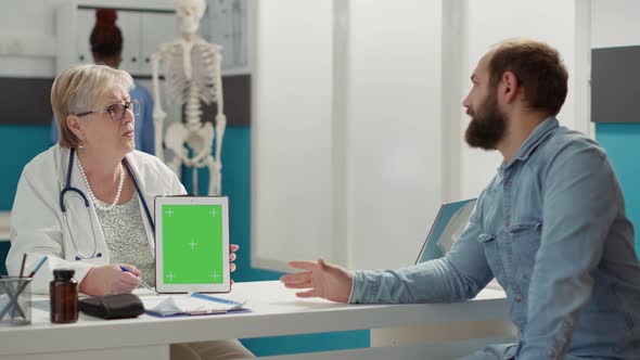 Doctor Vertically Holding Greenscreen on Digital Tablet in Cabinet