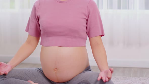 Close up Pregnant Woman deep breath with fresh air do yoga lotus pose comfortable at home